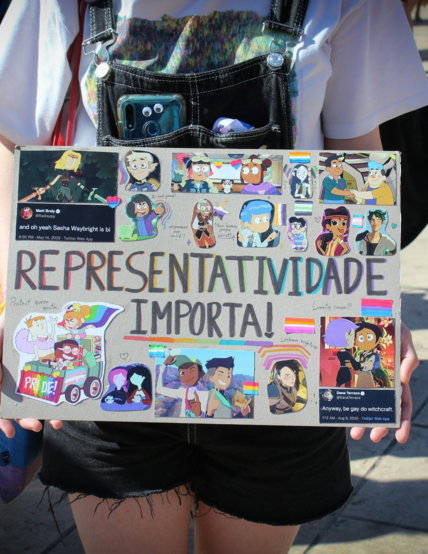 a-person-holding-a-sign-with-a-bunch-of-stickers-on-it.jpg a person holding a sign with a bunch of stickers on it